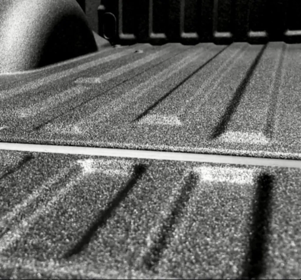 Close-up of polyurea coating on the bed of a white commercial work vehicle