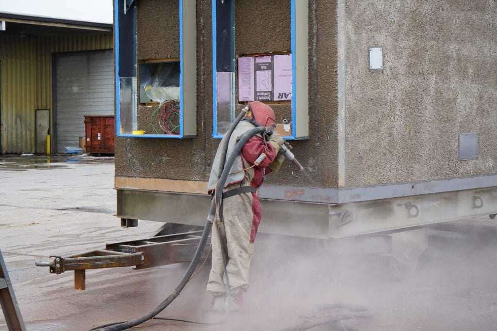 Technician applying polyurea to trailer exterior