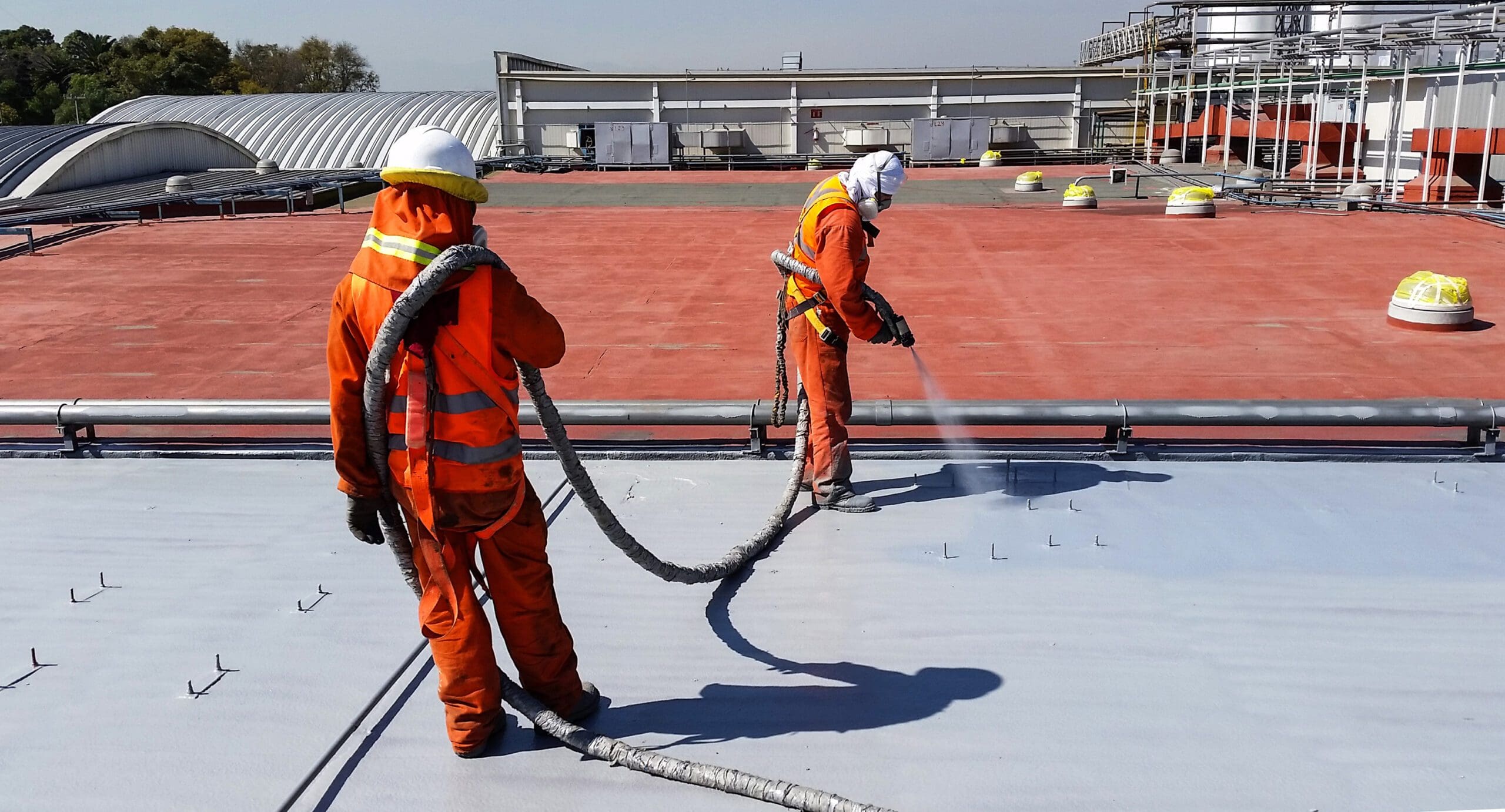 workers spraying polyurea on a factory roof
